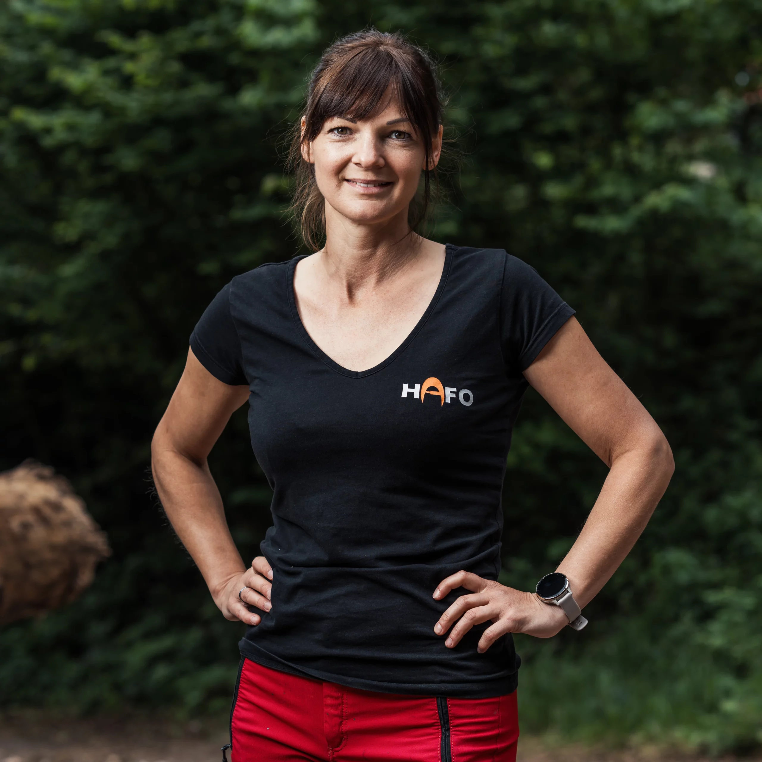 Eine Frau steht frontal zur Kamera und trägt ein schwarzes T-Shirt mit dem Aufdruck HAFO.